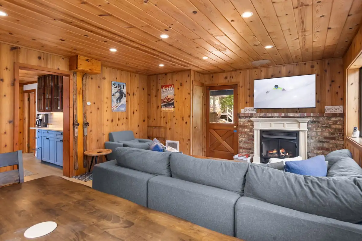 Living room with a large gray sectional and brick fireplace, Homewood Cabin in the Pines
