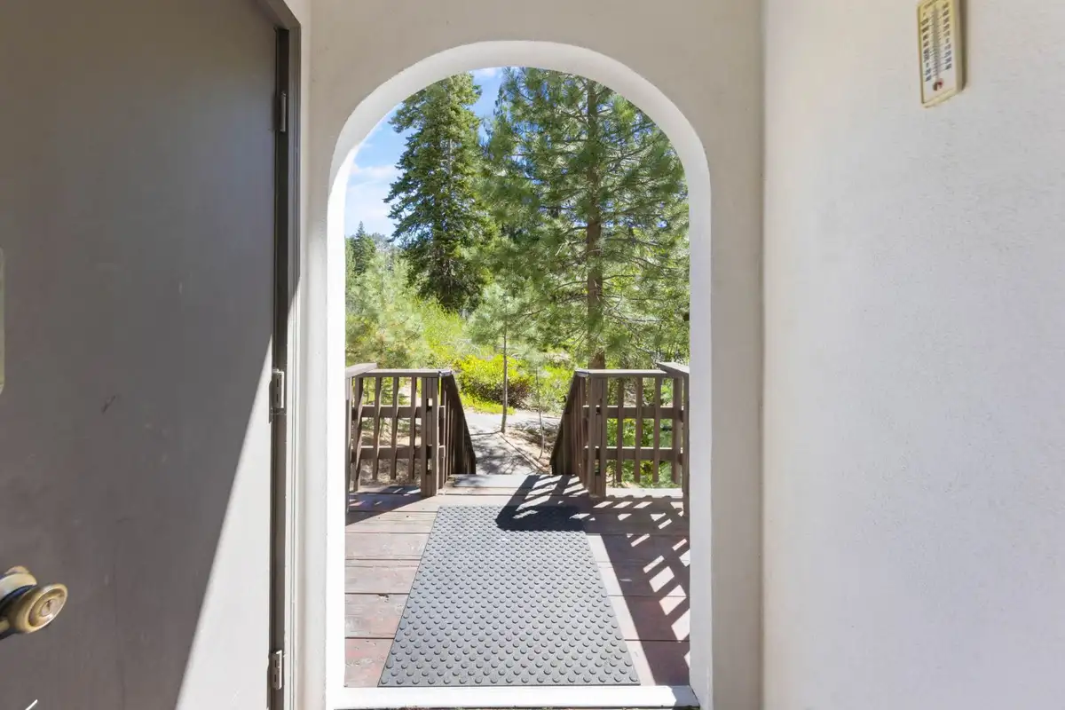 Arched front doorway opening to a deck and pines, Cortina Chalet