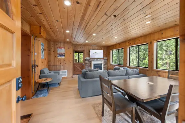 Knotty pine living room with a dining table and gray sofa, Homewood Cabin in the Pines