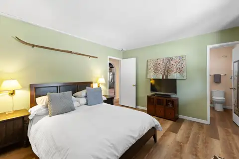 Green bedroom with a bed, TV and attached bathroom, Cortina Chalet