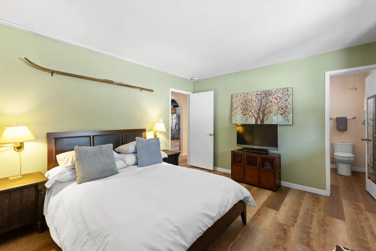 Green bedroom with a bed, TV and attached bathroom, Cortina Chalet