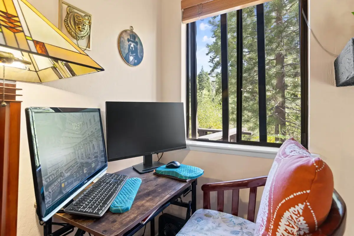 Desk nook with computer monitors beside a window, Cortina Chalet