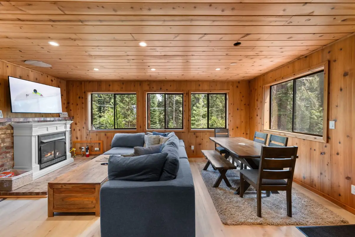Living room with a fireplace, gray sofa and dining table, Homewood Cabin in the Pines