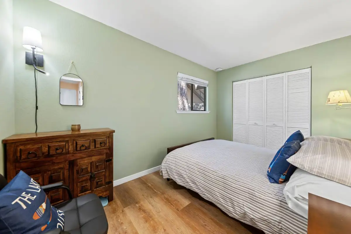 Green bedroom with a bed and wood dresser, Cortina Chalet