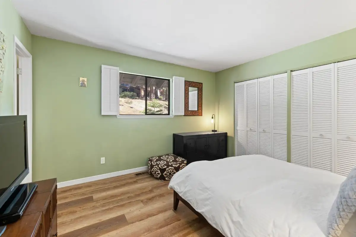 Green bedroom with a bed and louvered closet doors, Cortina Chalet