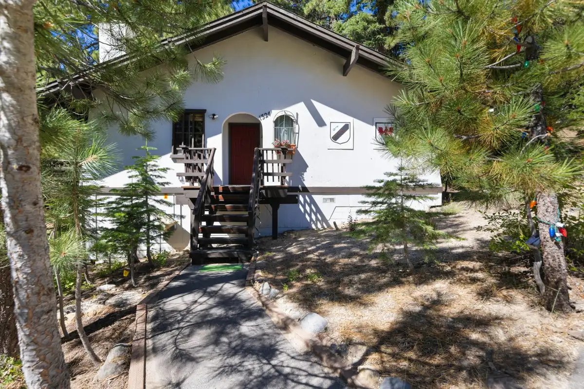 White chalet-style home with front stairs among pines, Cortina Chalet