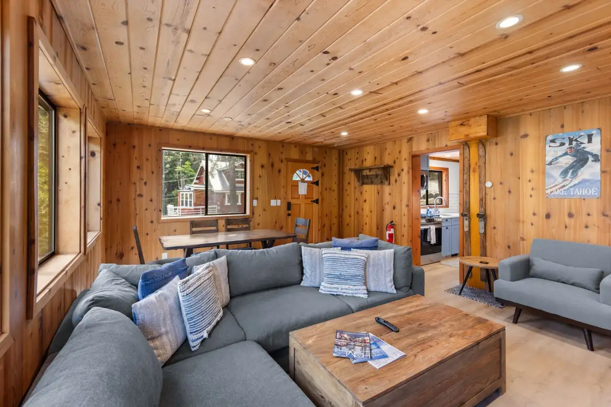 Pine-paneled living room with a gray sectional and wood coffee table, Homewood Cabin in the Pines