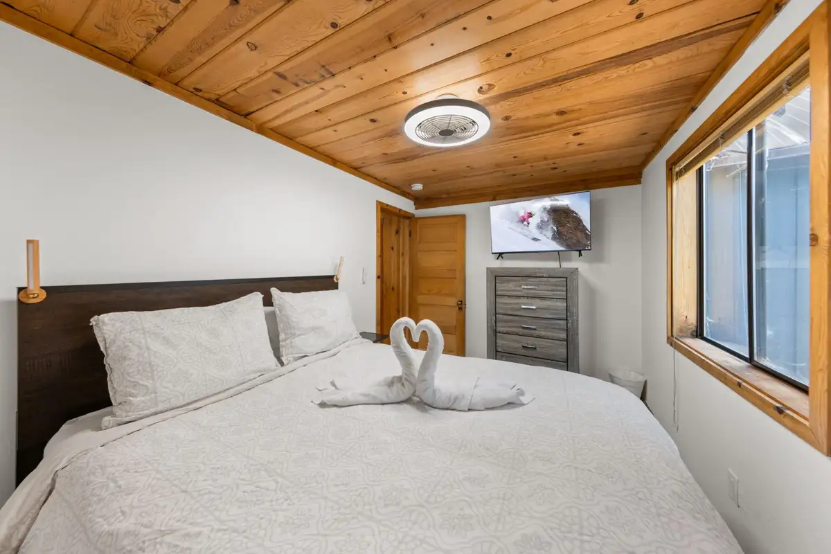 Bedroom with a bed, towel swans and pine ceiling, Homewood Cabin in the Pines