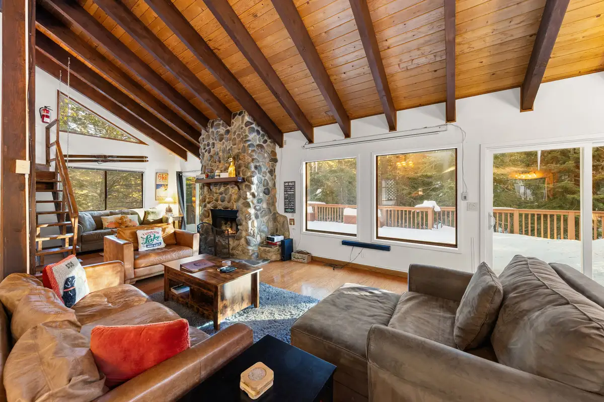 Living room with stone fireplace and leather sofas, Sierra Woodlands Getaway