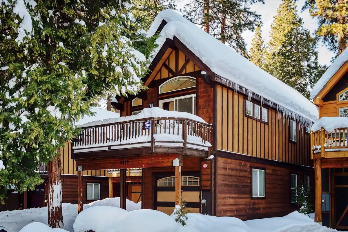 Two-story wood cabin with a balcony in deep snow, Trout and About
