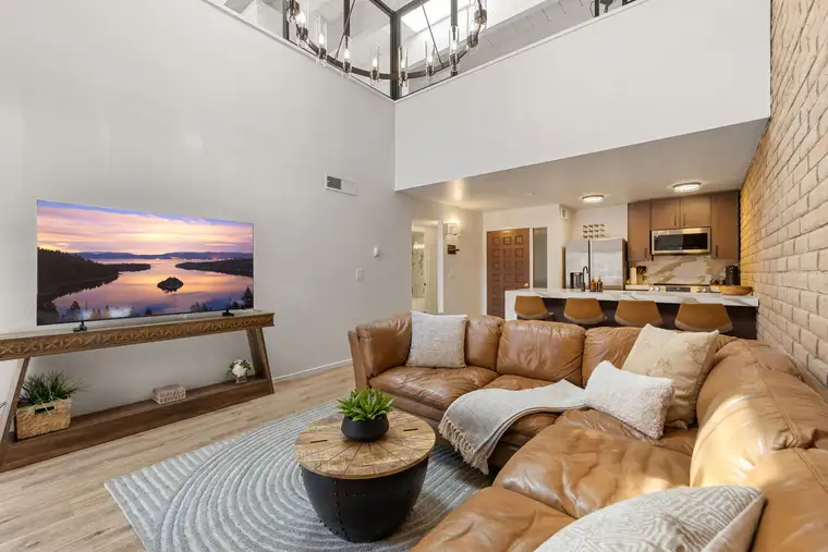 Open-concept living area with marble kitchen island, stone fireplace, and vaulted ceilings