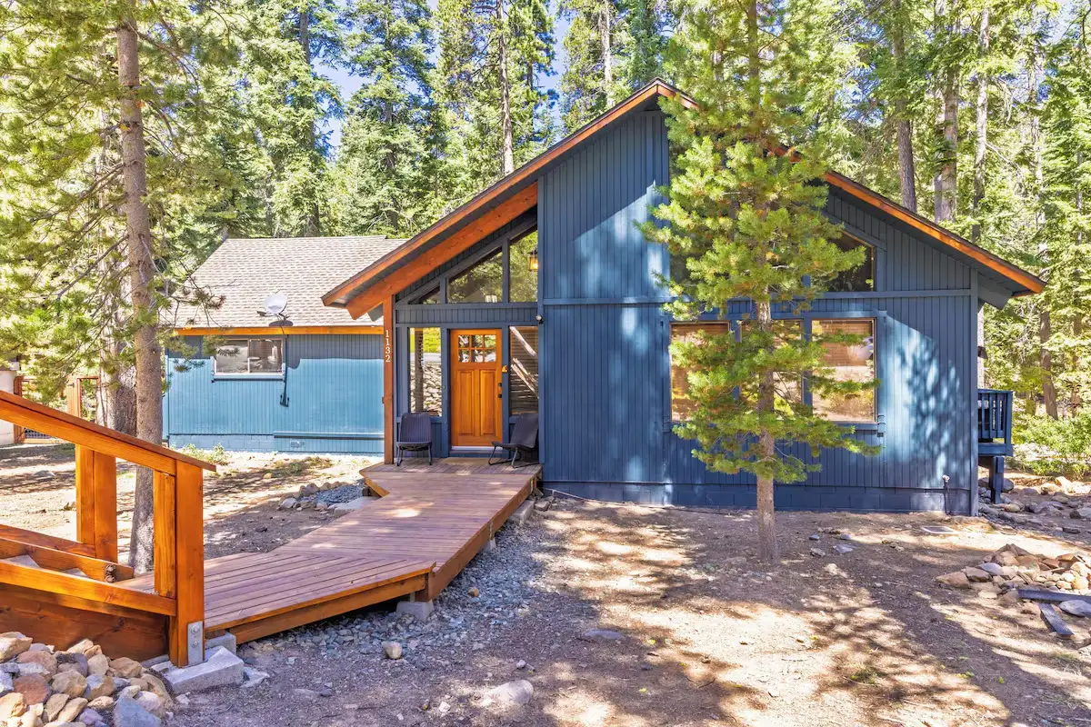 Dark blue A-frame cabin among pines with a wooden deck, Grand Regency Retreat