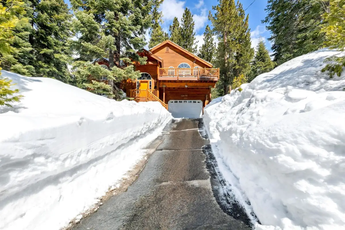 Plowed driveway between snowbanks leading to a wood home, Hastings Hideaway Cabin