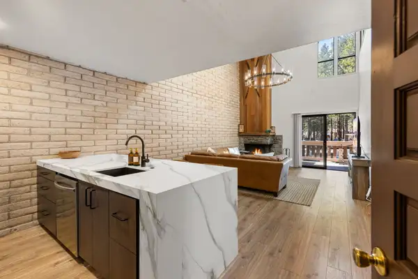 Marble waterfall kitchen island with brick accent wall and cozy fireplace, Treetop on Country Club