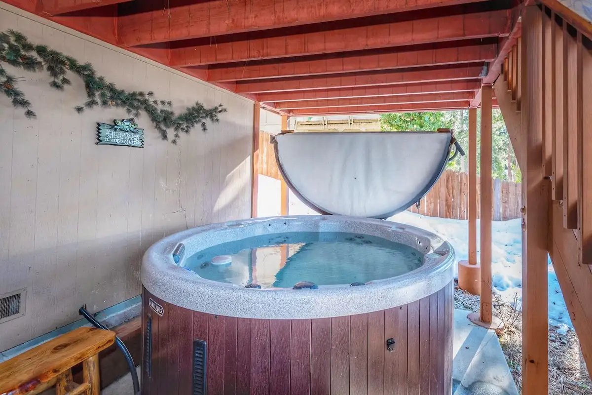 Hot tub under a covered deck with an open lid, Lakeview Serenity Cottage