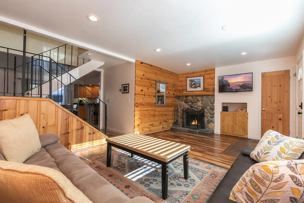 Living room with stone fireplace and wood-paneled wall, Trailside Tahoe Townhouse