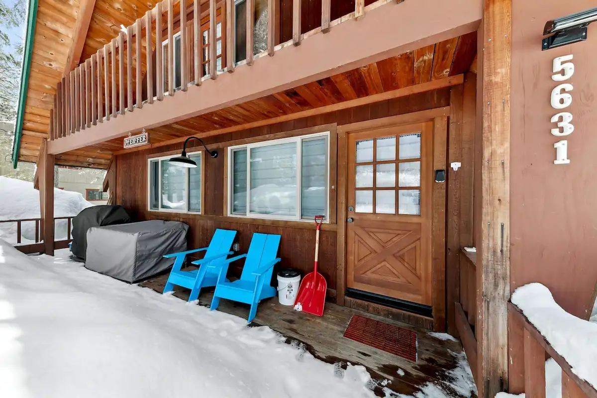 Front porch with blue chairs and wood door in snow, Patton's Pfeiffer Cabin