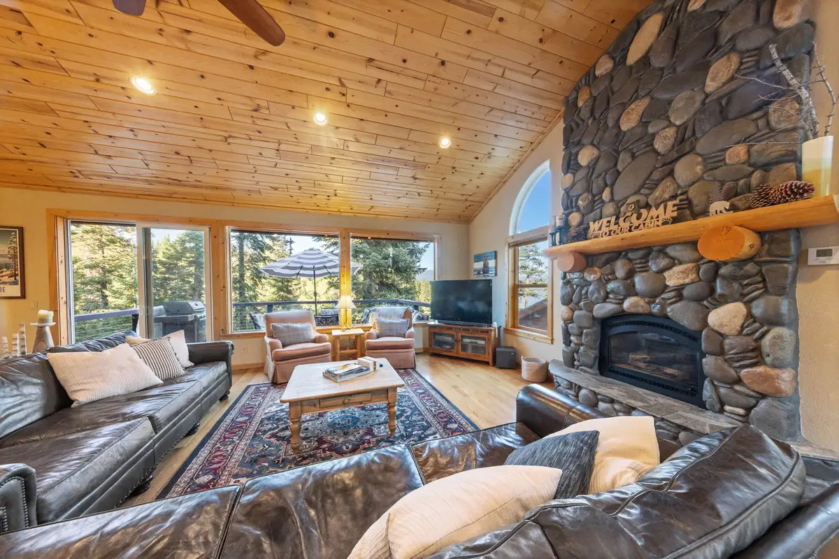 Living room with river rock fireplace and leather sofas, Lakeview Grandeur