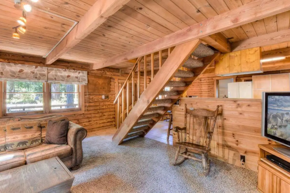 Log cabin living room with a staircase and rocking chair, Enchanted Woods Cabin