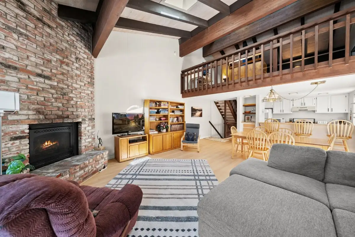 Living room with brick fireplace and dining area beyond, Skiway Suite