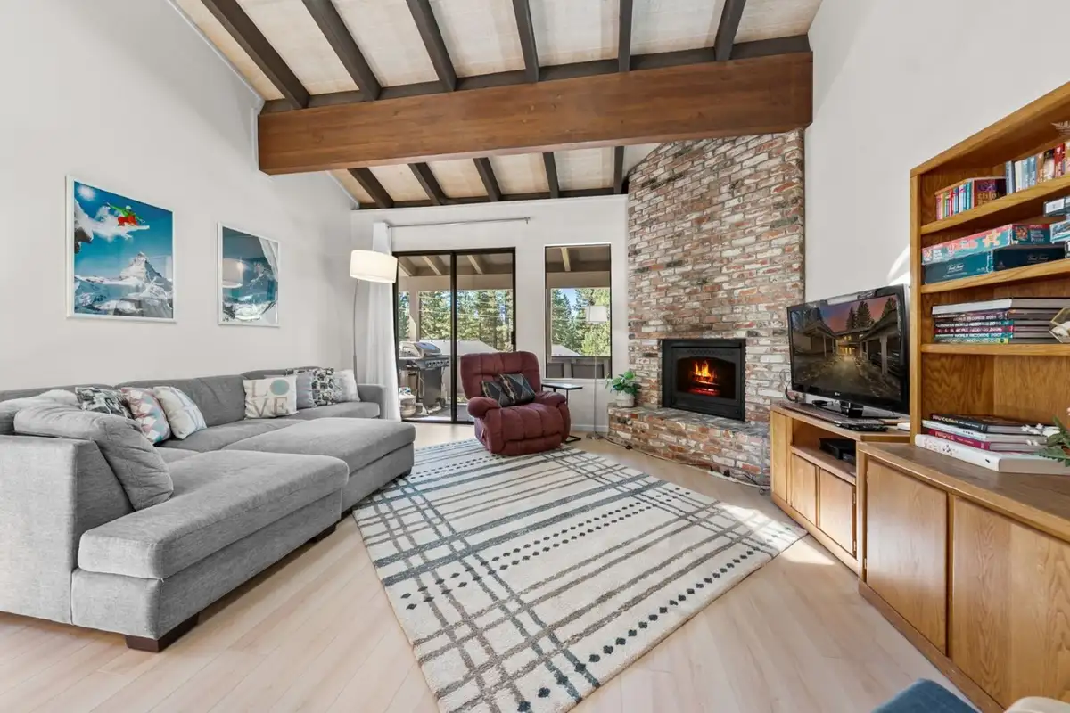 Living room with gray sectional and brick fireplace, Skiway Suite