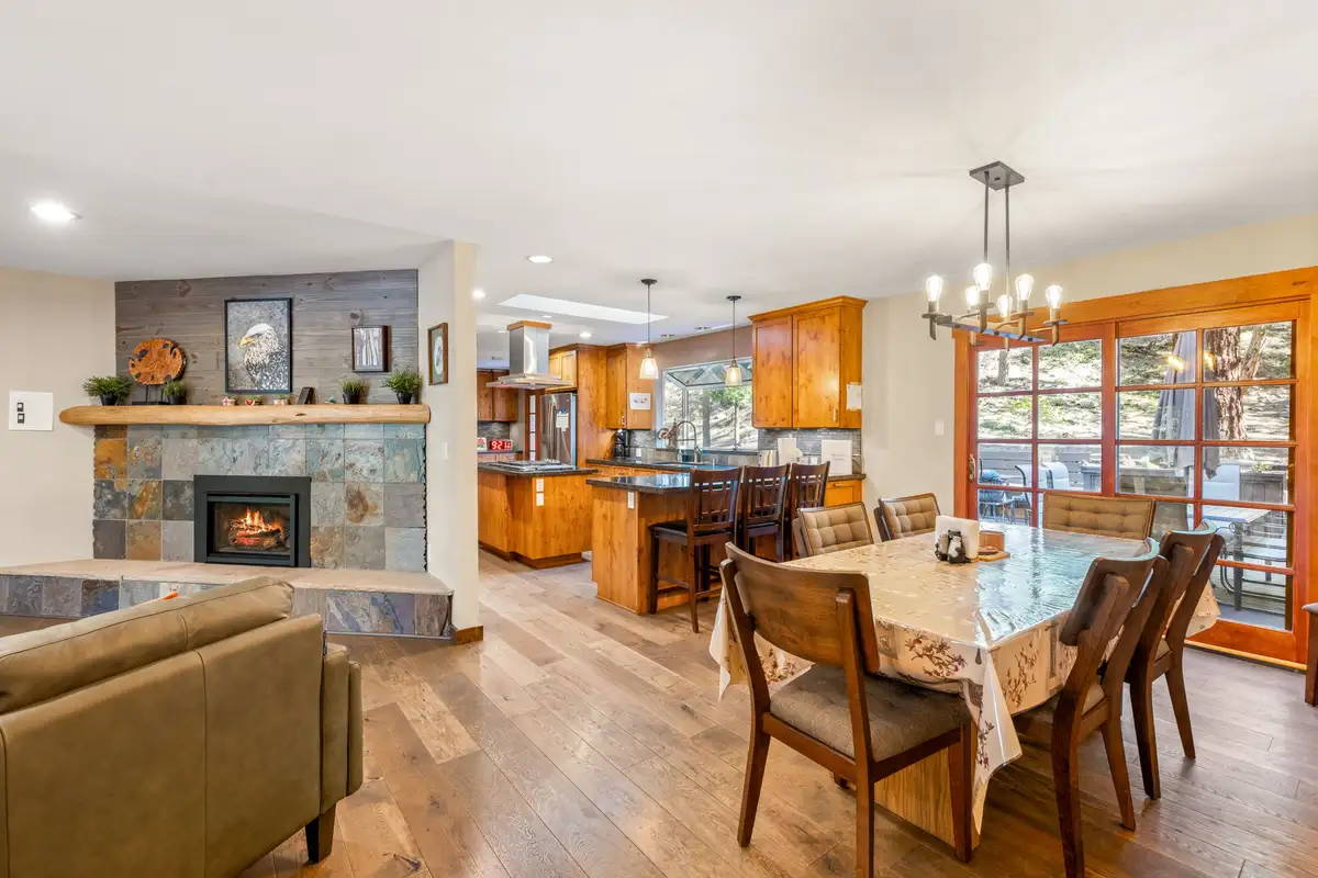 Dining table under a chandelier near the fireplace and kitchen, Tranquil Stay