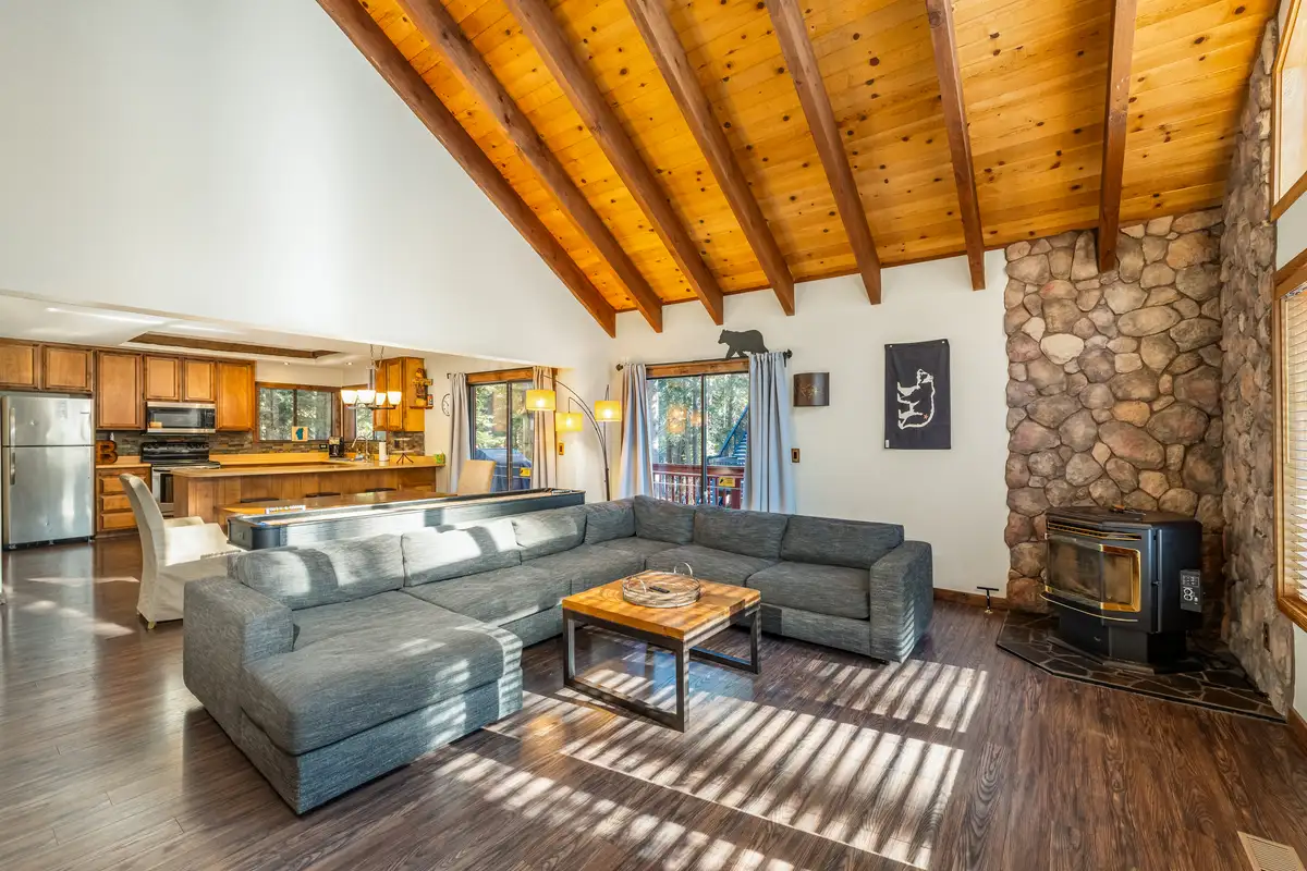 Living room with gray sectional and stone wall with stove, Grand Regency Retreat