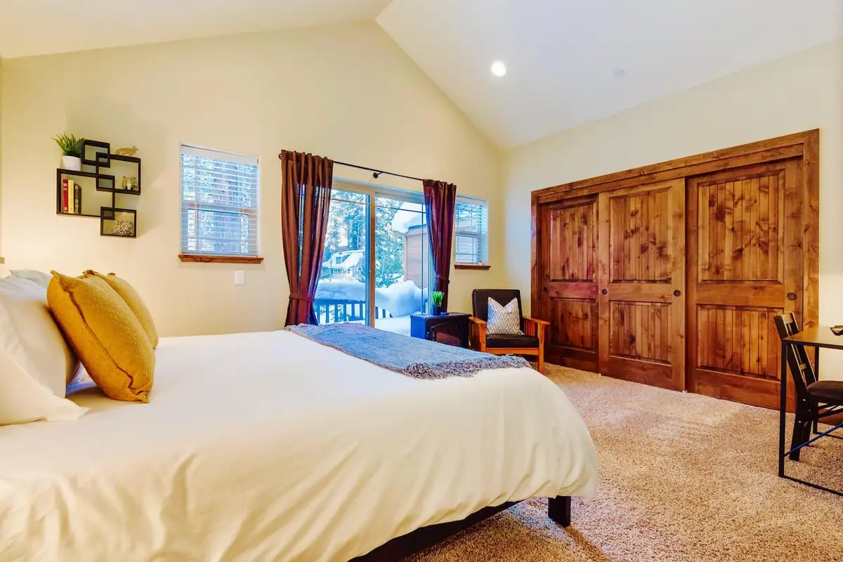 Bedroom with vaulted ceiling and sliding doors to a snowy deck, Trout and About