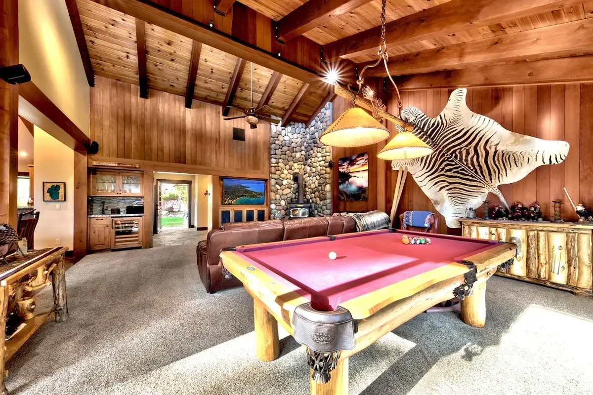 Pool table under pendant lights with a stone fireplace behind, Mammoth Haven Retreat