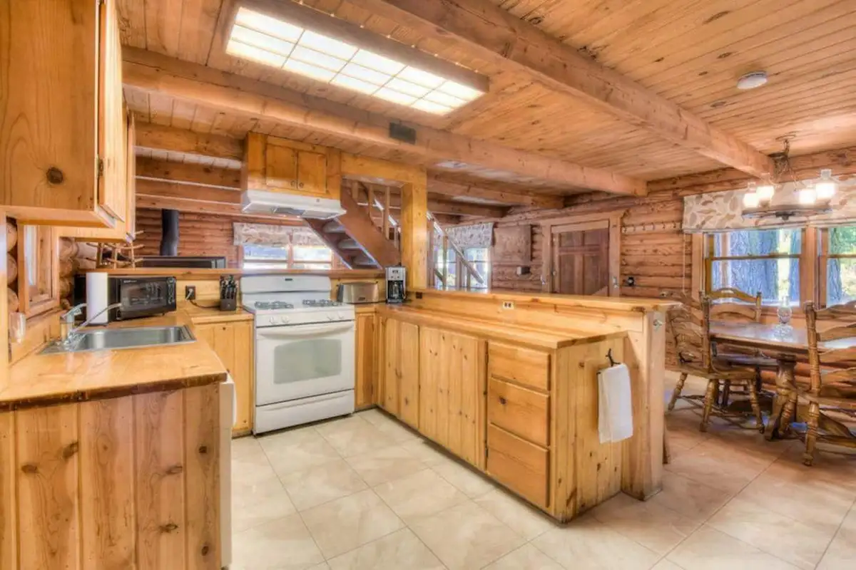 Pine kitchen with a white range and dining table beyond, Enchanted Woods Cabin