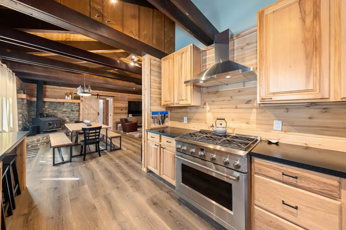 Kitchen with gas range opening to dining area and wood stove, Updated West Shore Cabin 1 mile to Chambers Beach