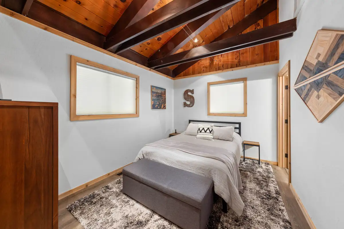 Bedroom with a bed, bench and exposed wood beams, Updated West Shore Cabin 1 mile to Chambers Beach