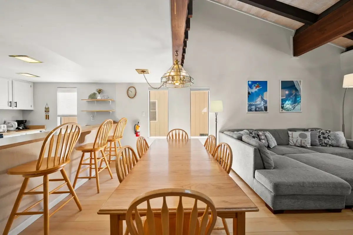 Long dining table with wooden chairs next to living area, Skiway Suite