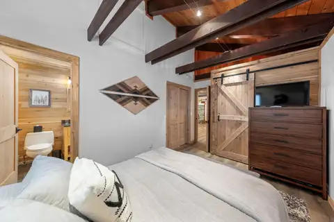 Bedroom with a bed, dresser and sliding barn door, Updated West Shore Cabin 1 mile to Chambers Beach