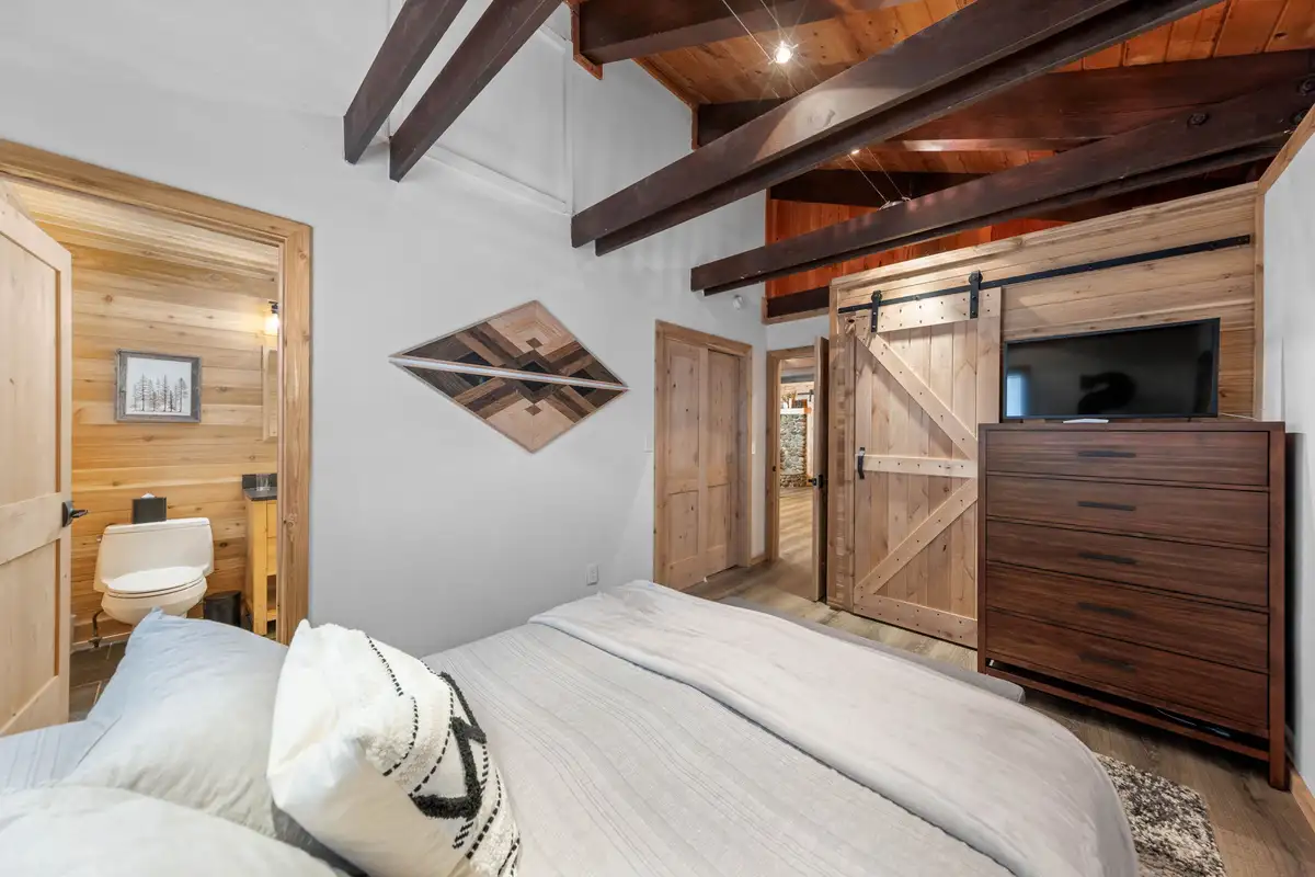 Bedroom with a bed, dresser and sliding barn door, Updated West Shore Cabin 1 mile to Chambers Beach