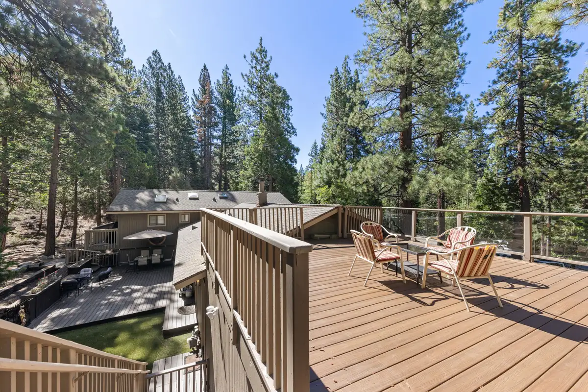 Upper deck with chairs and table overlooking pine trees, Tranquil Stay