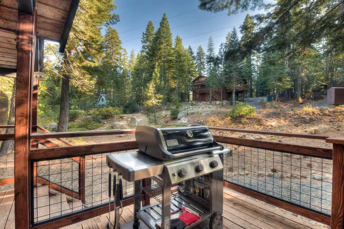 Covered deck with a grill and wire railing facing the forest, Enchanting Chamberlands Cabin