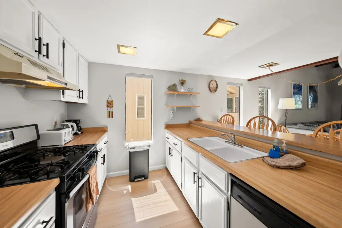 Galley kitchen with gas range and white cabinets, Skiway Suite