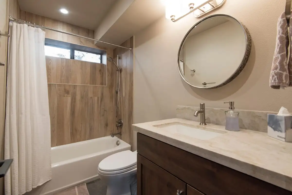 Bathroom with a tub-shower and round mirror, Tranquil Tahoe Haven