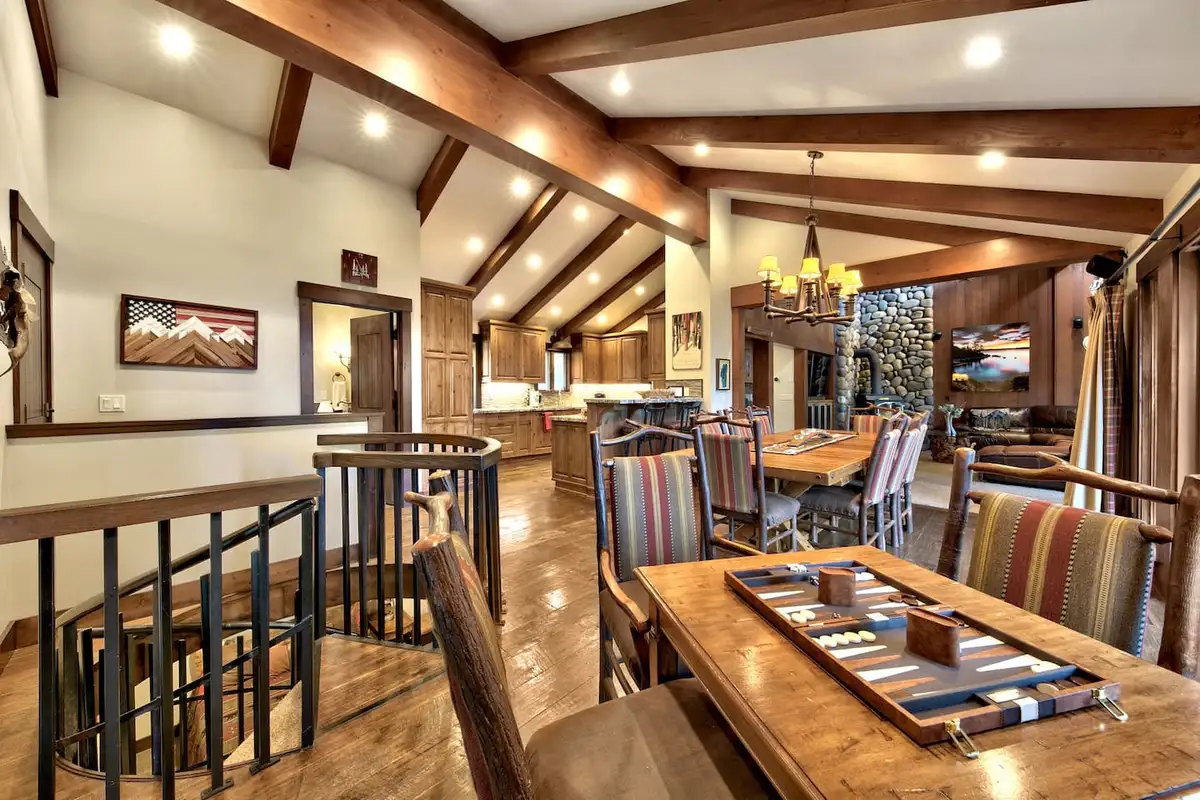 Dining table with a game board near a spiral staircase, Mammoth Haven Retreat