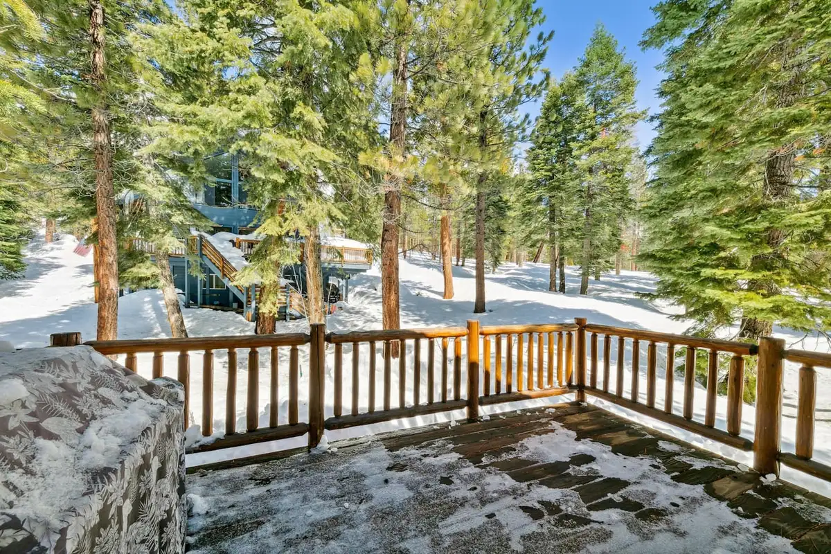 Deck with log railings overlooking a snowy forest, Hastings Hideaway Cabin
