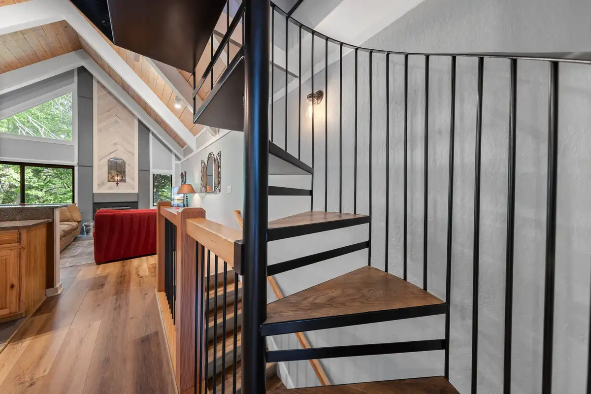Spiral staircase beside an open living area with wood floors, Tahoe Peaks & Shores Retreat