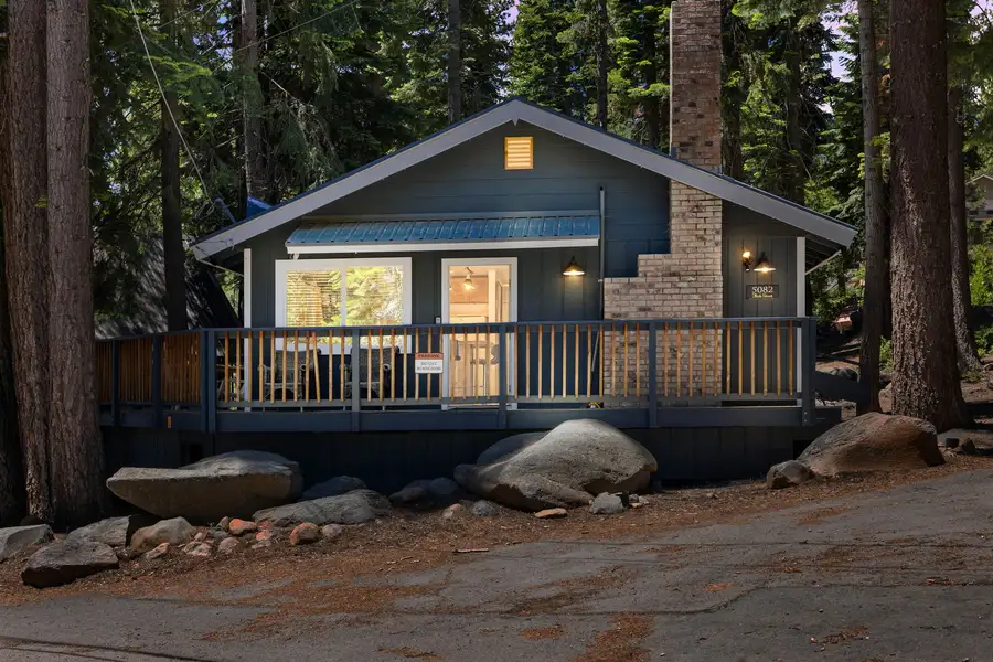 Blue cabin with lit windows and a front deck at dusk, Tahoe Lake & Mountain Retreat