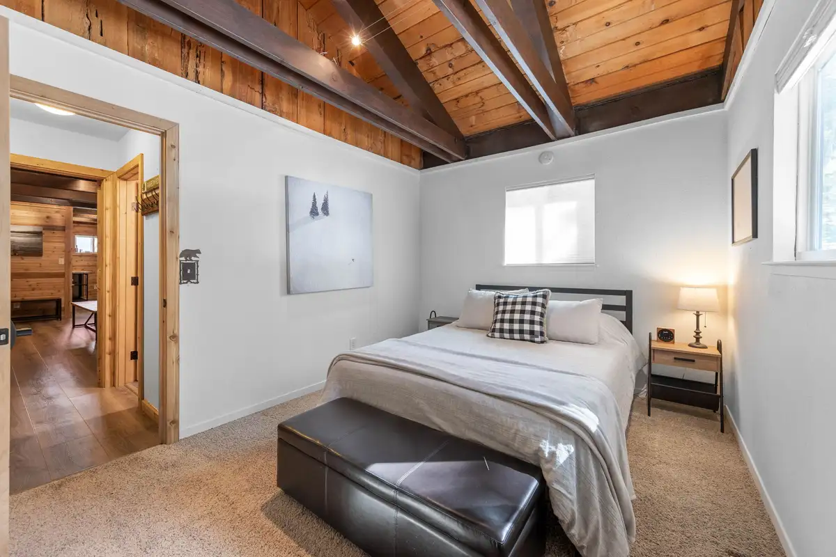 Bedroom with a bed and leather bench at its foot, Updated West Shore Cabin 1 mile to Chambers Beach