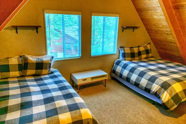 A-frame bedroom with two beds and checkered bedding, Enchanting Chamberlands Cabin