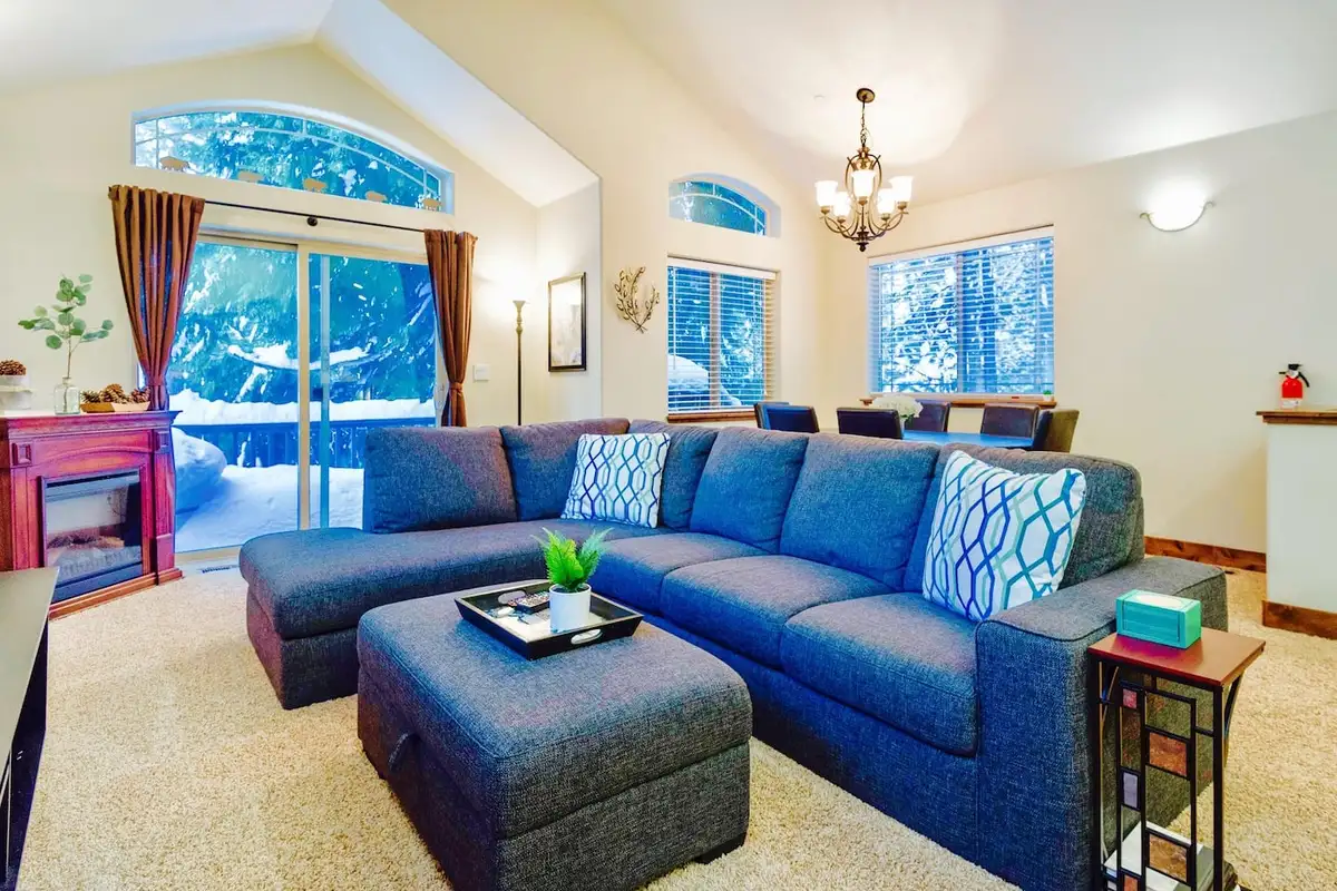 Gray sectional sofa facing sliding doors to a snowy yard, Trout and About