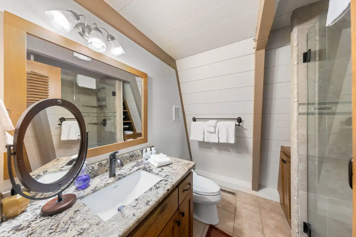 Bathroom with granite vanity and round mirror, Livin' on the Edge