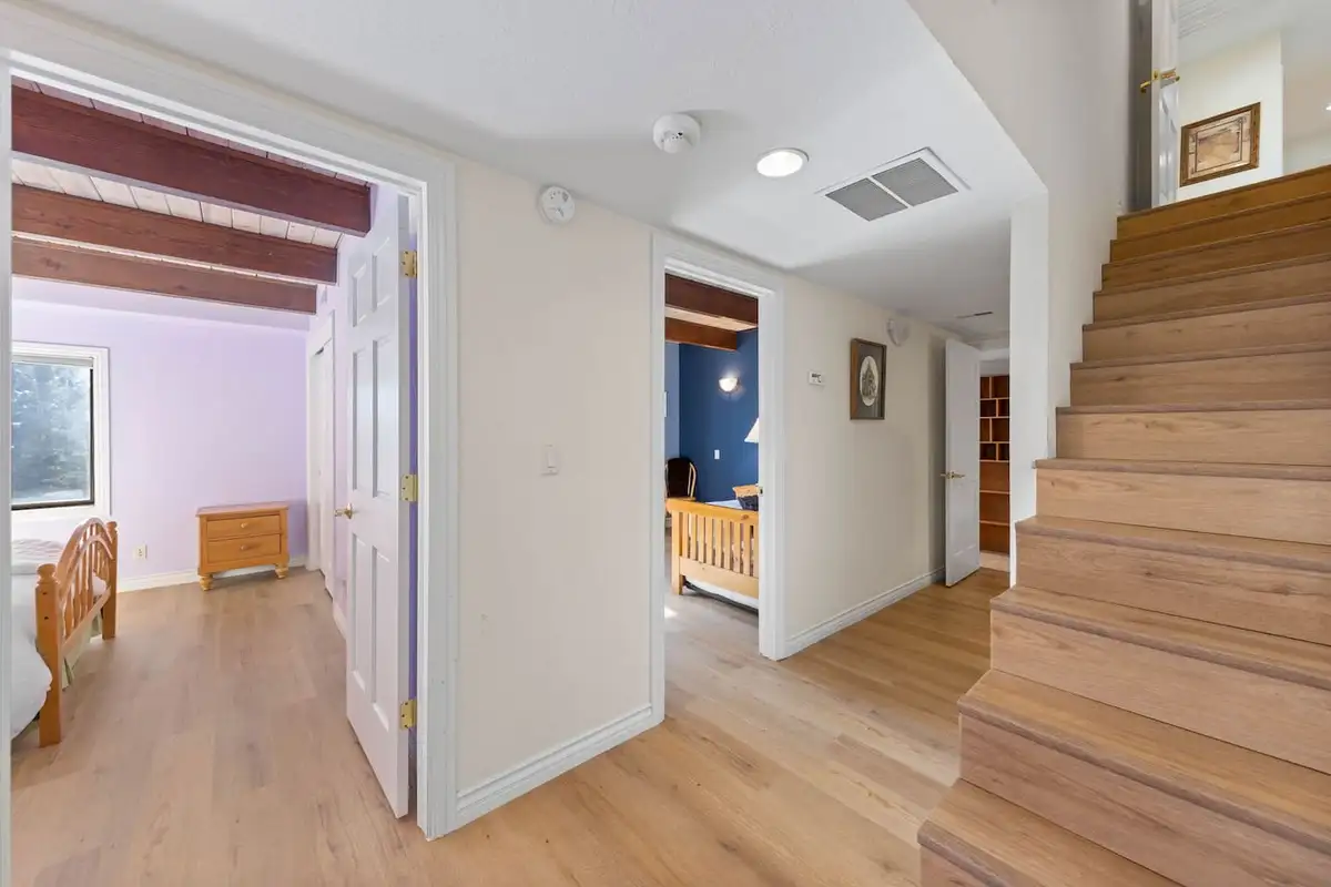 Hallway with a wood staircase and doorways to bedrooms, Tranquil Alpine Bliss