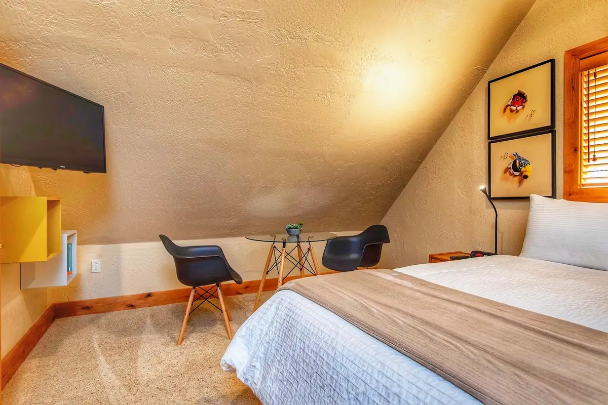 Bedroom under a sloped ceiling with a bed and wall TV, Restful North Ridge
