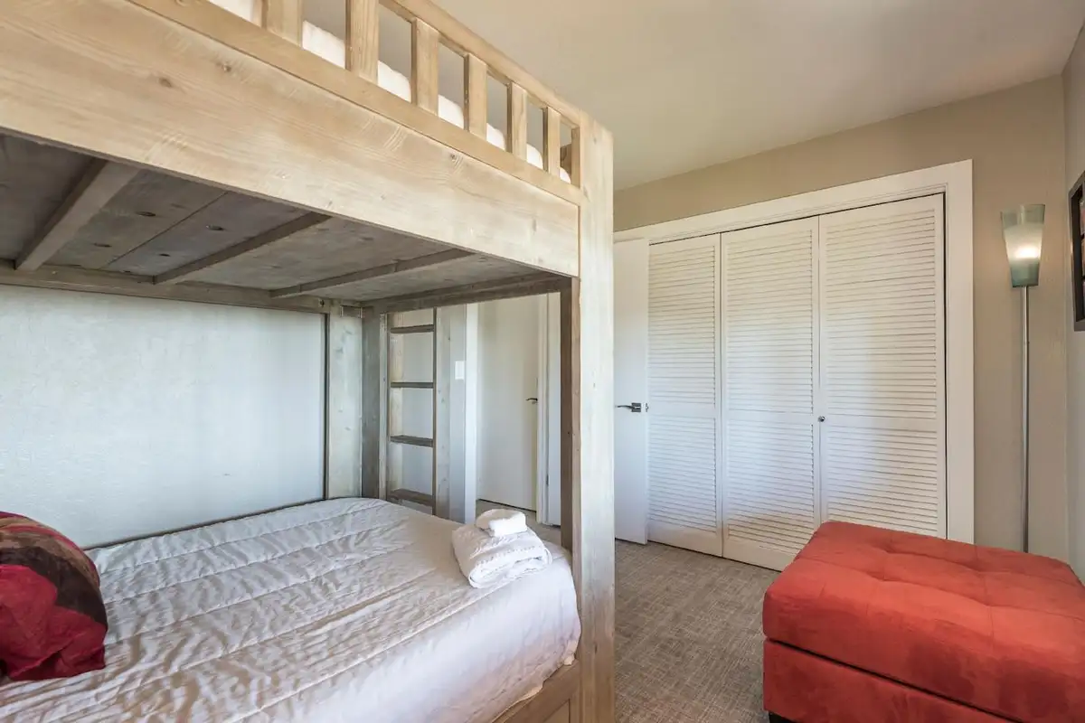 Wood bunk bed with a red ottoman and closet, Skylake Serenity Retreat